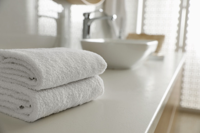 Photo of Stack of clean towels on countertop in bathroom. Space for text