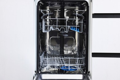 Photo of Open clean empty dishwasher machine. Home appliance