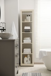 Photo of Stylish bathroom interior with grey chest of drawers and shelving unit