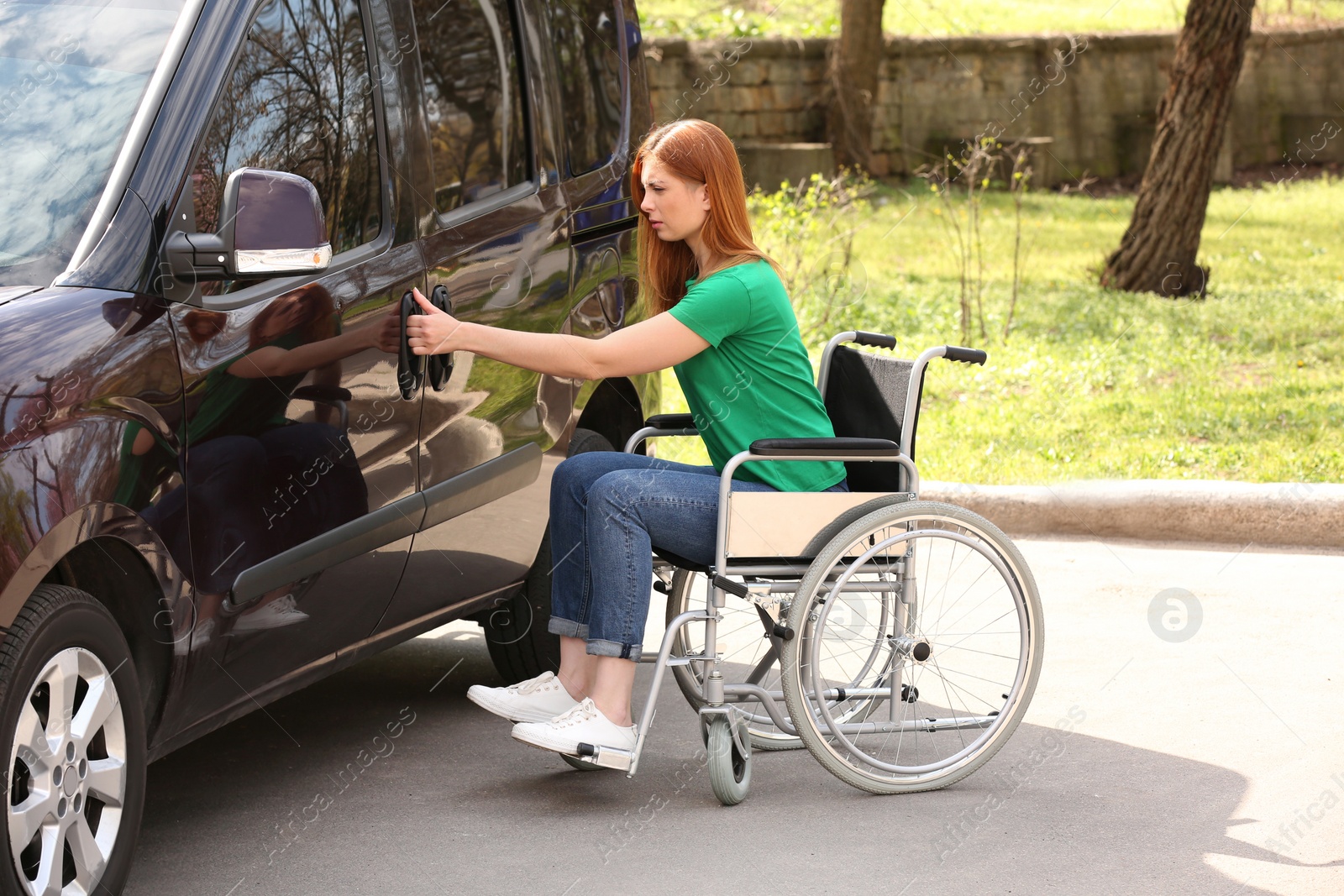 Photo of Woman in wheelchair opening door of her van outdoors