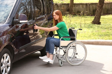 Photo of Woman in wheelchair opening door of her van outdoors