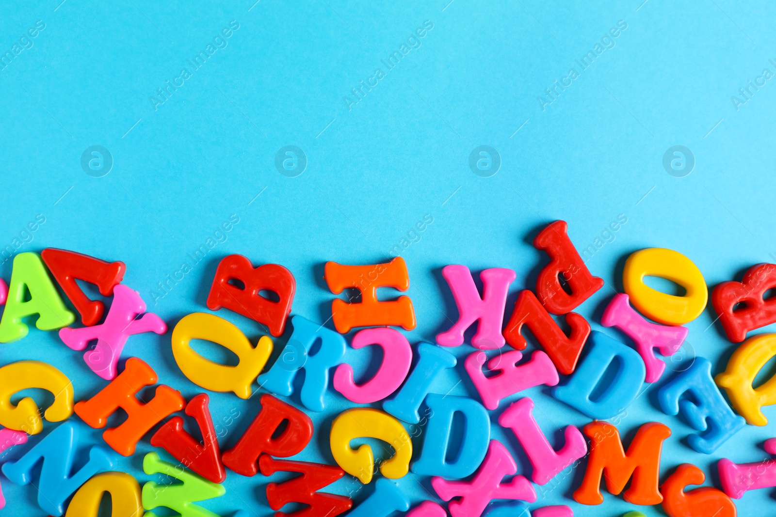 Photo of Many colorful magnetic letters on light blue background, flat lay. Space for text