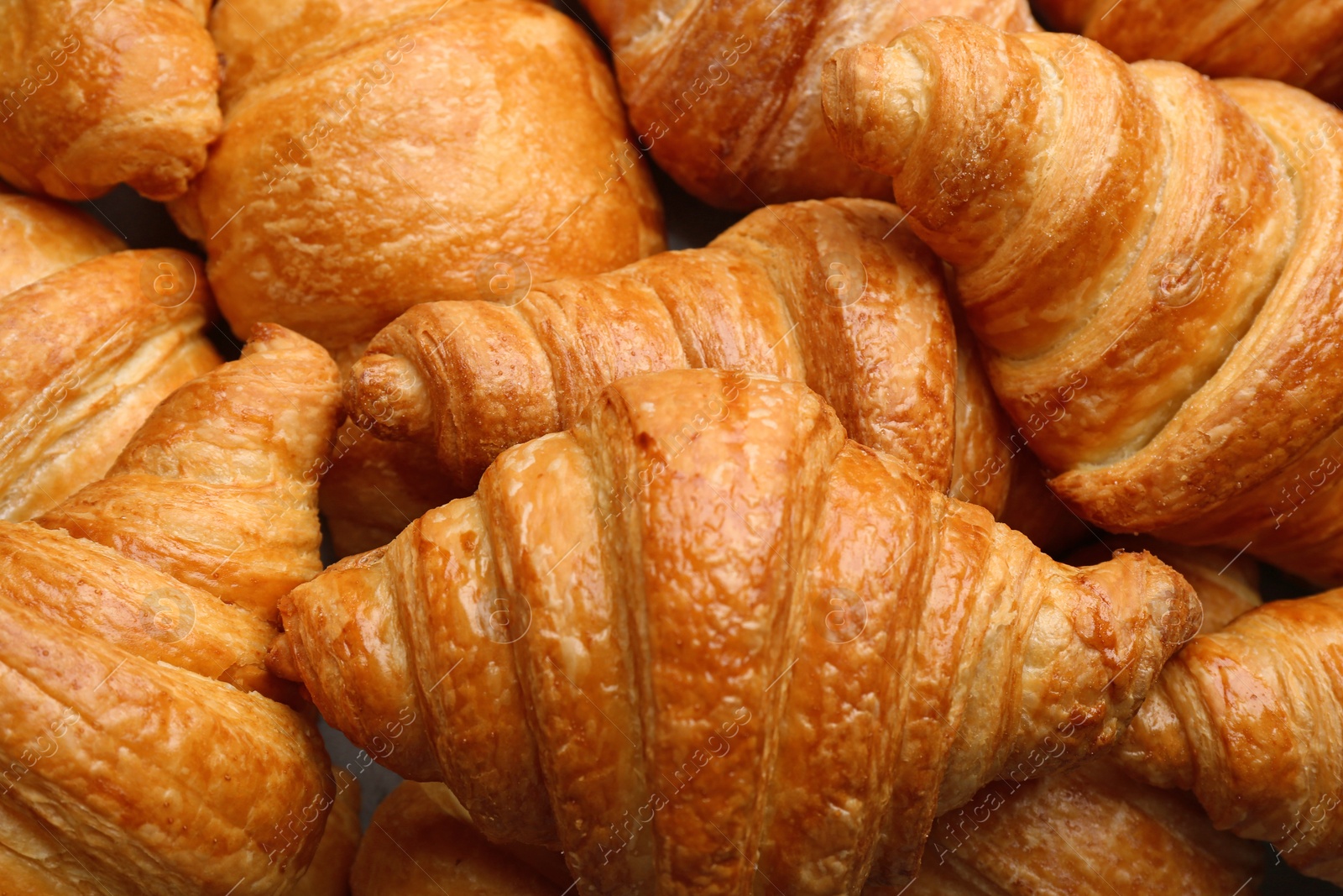 Photo of Fresh tasty croissants as background, closeup. French pastry