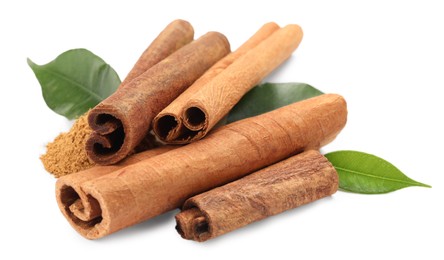 Photo of Dry aromatic cinnamon sticks, powder and green leaves isolated on white