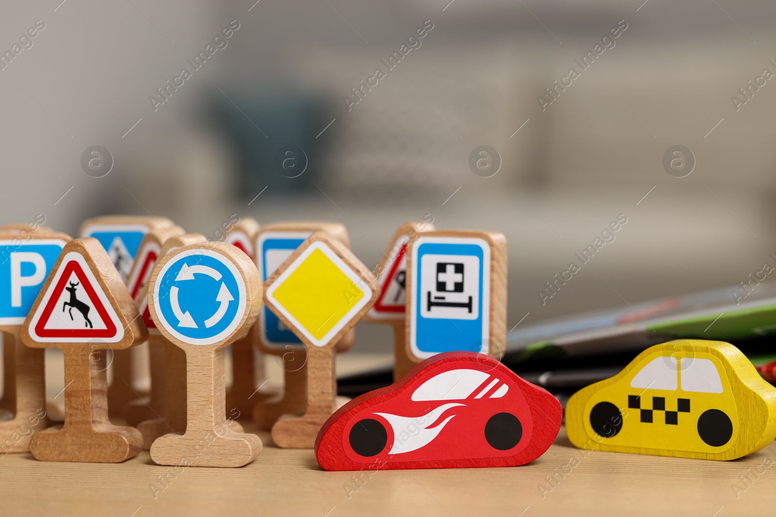 Photo of Set of wooden road signs and cars on table indoors, closeup. Children's toys