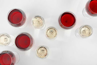 Photo of Glass of red and white wines on light background, top view
