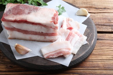 Photo of Tasty salt pork with garlic and parsley on wooden table