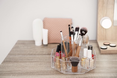 Organizer with cosmetic products for makeup on table near mirror