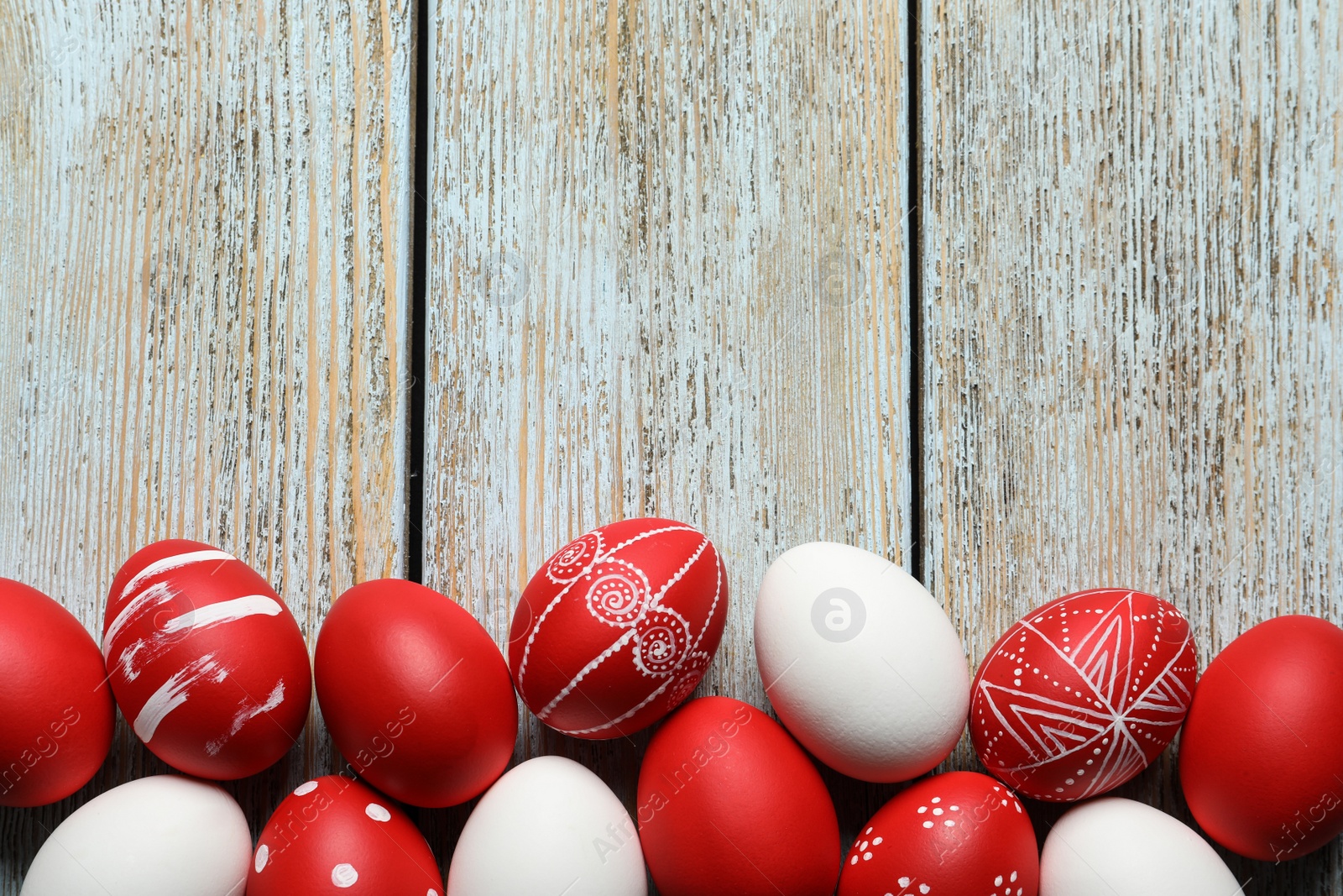 Photo of Flat lay composition of painted red Easter eggs on wooden table, space for text