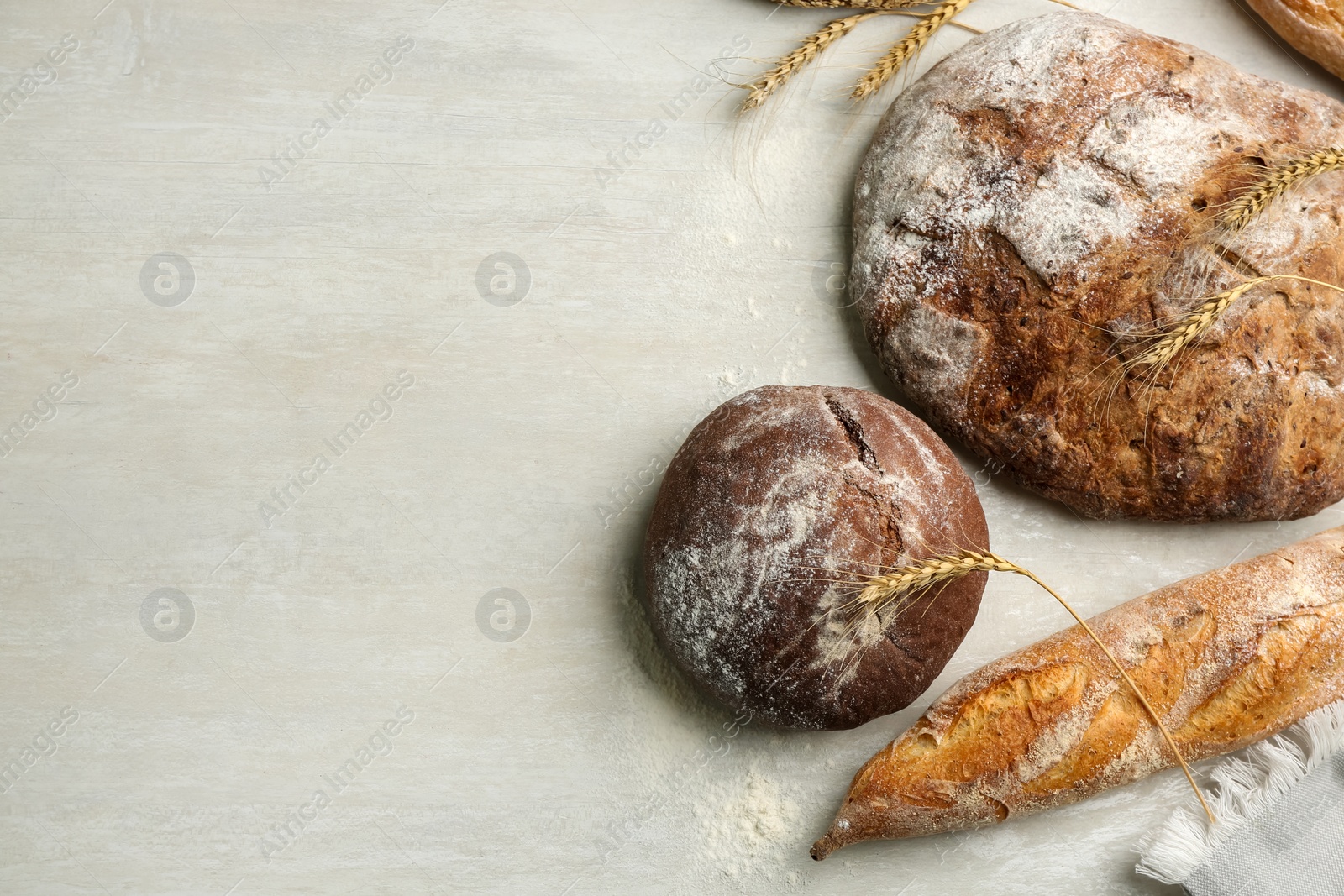 Photo of Different kinds of fresh bread on white wooden table, flat lay. Space for text