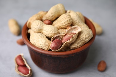 Photo of Fresh unpeeled peanuts in bowl on grey table, closeup