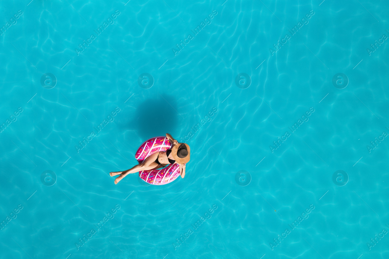 Image of Young happy woman with inflatable ring in swimming pool, top view. Summer vacation