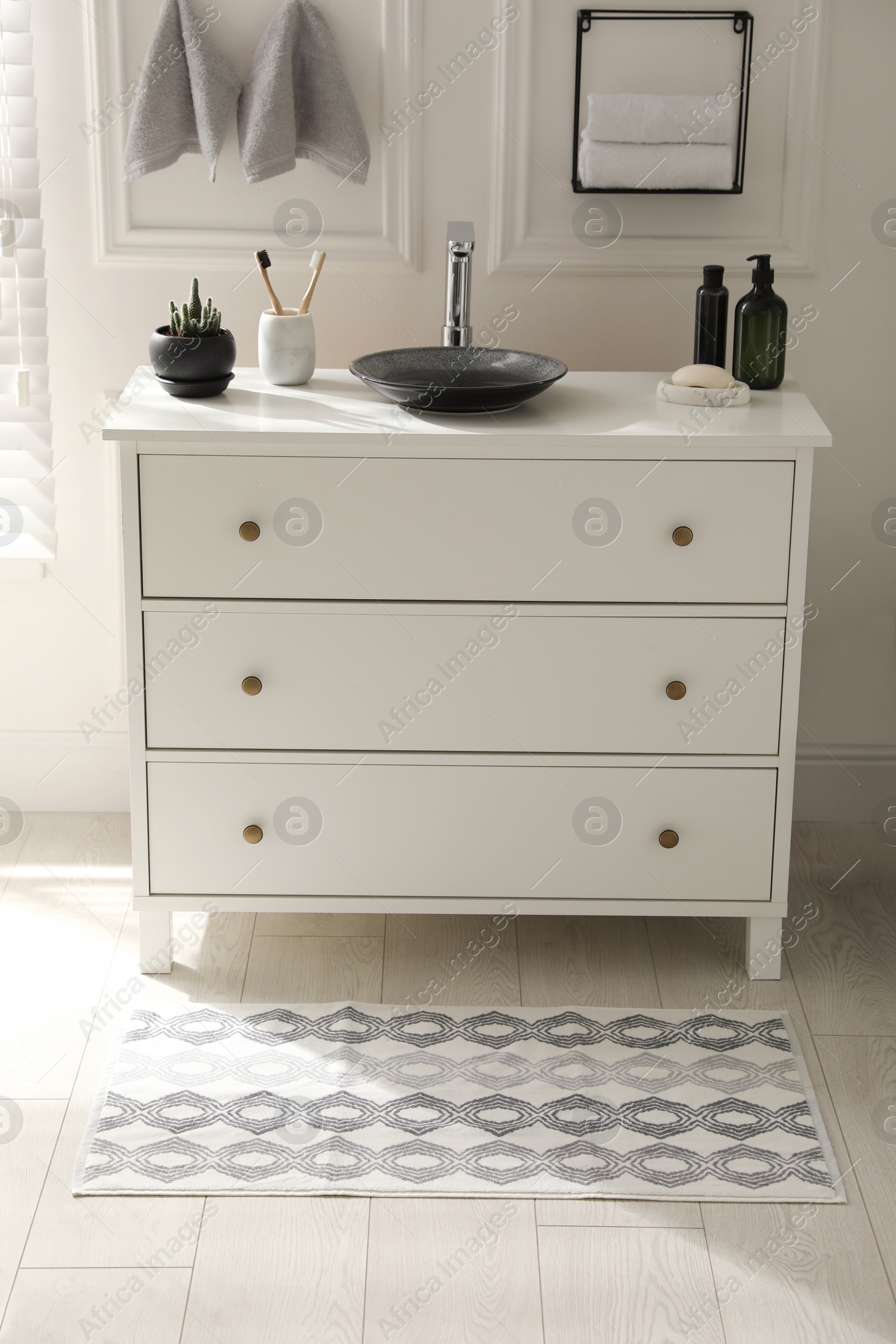 Photo of Stylish mat with pattern near chest of drawers in bathroom