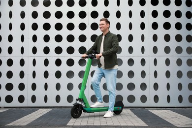 Happy man with modern electric kick scooter on city street