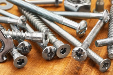 Photo of Many different fasteners on wooden table, closeup