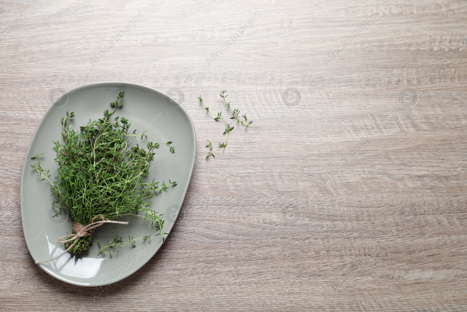 Photo of Bunch of aromatic thyme on wooden table, top view. Space for text