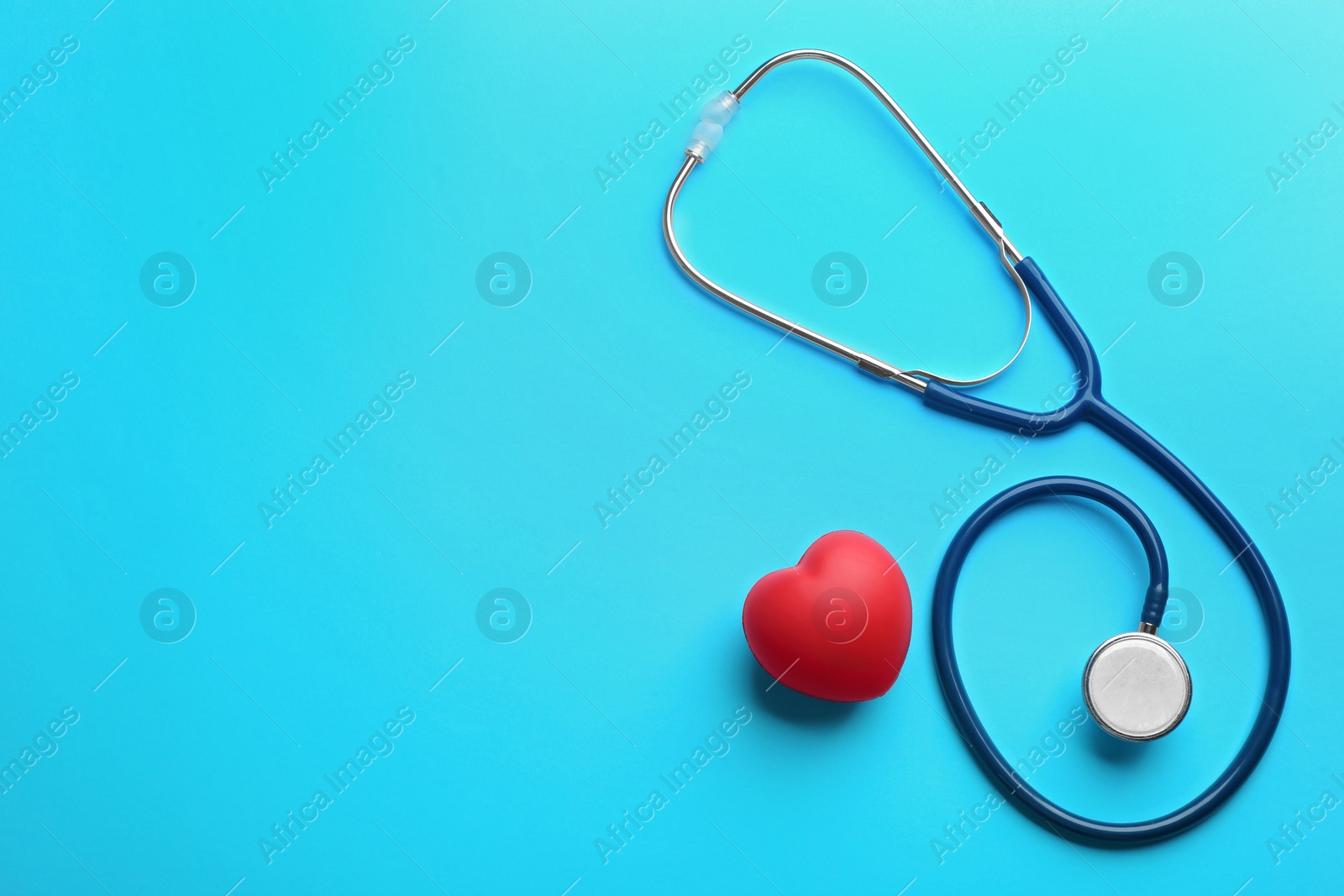 Photo of Stethoscope and red heart on blue background, flat lay with space for text