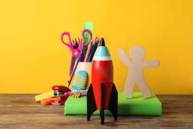 Bright toy rocket and school supplies on wooden desk