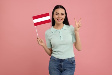 Image of Happy young woman with flag of Austria showing V-sign on pink background