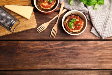 Photo of Baked eggplant with tomatoes, cheese and basil served on wooden table, flat lay. Space for text