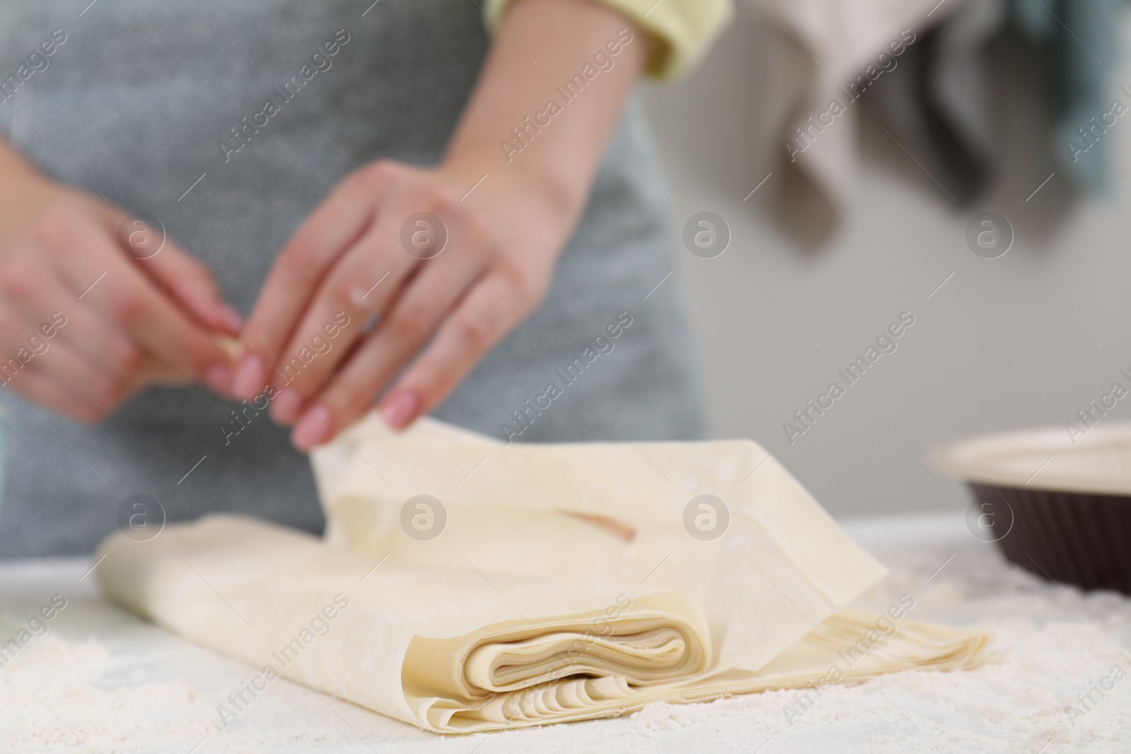 Photo of Making tasty baklava. Woman with dough at table, closeup