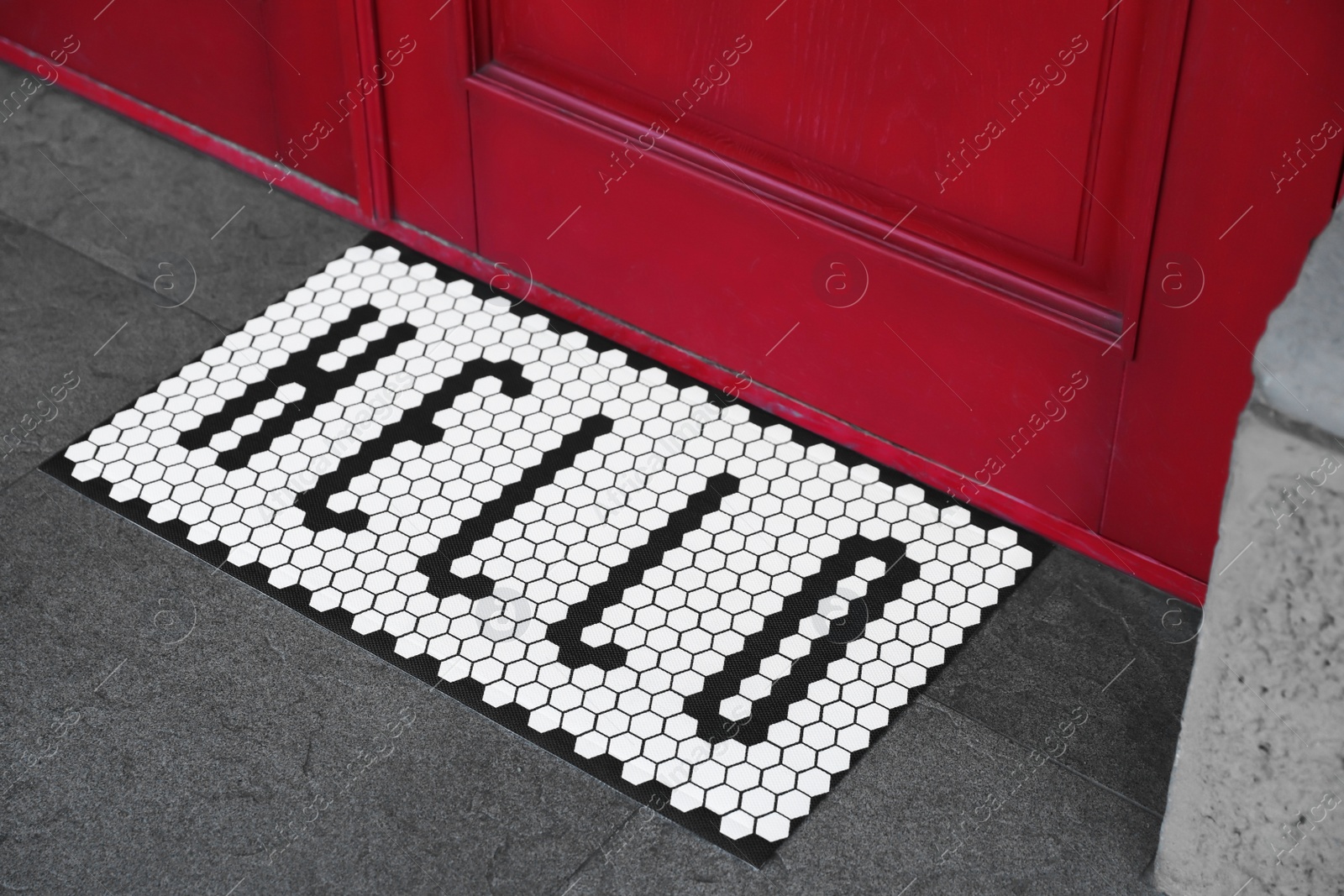 Photo of Stylish door mat with word HELLO near entrance