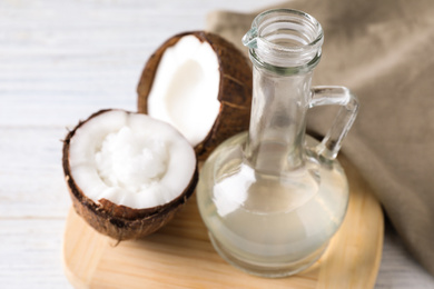 Photo of Coconut oil in glass jug on white table, closeup