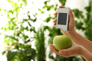 Photo of Woman checking apple with nitrate tester on blurred background, closeup. Space for text