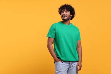 Handsome smiling man on yellow background, space for text