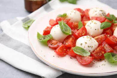 Photo of Tasty salad Caprese with tomatoes, mozzarella balls and basil on table, closeup