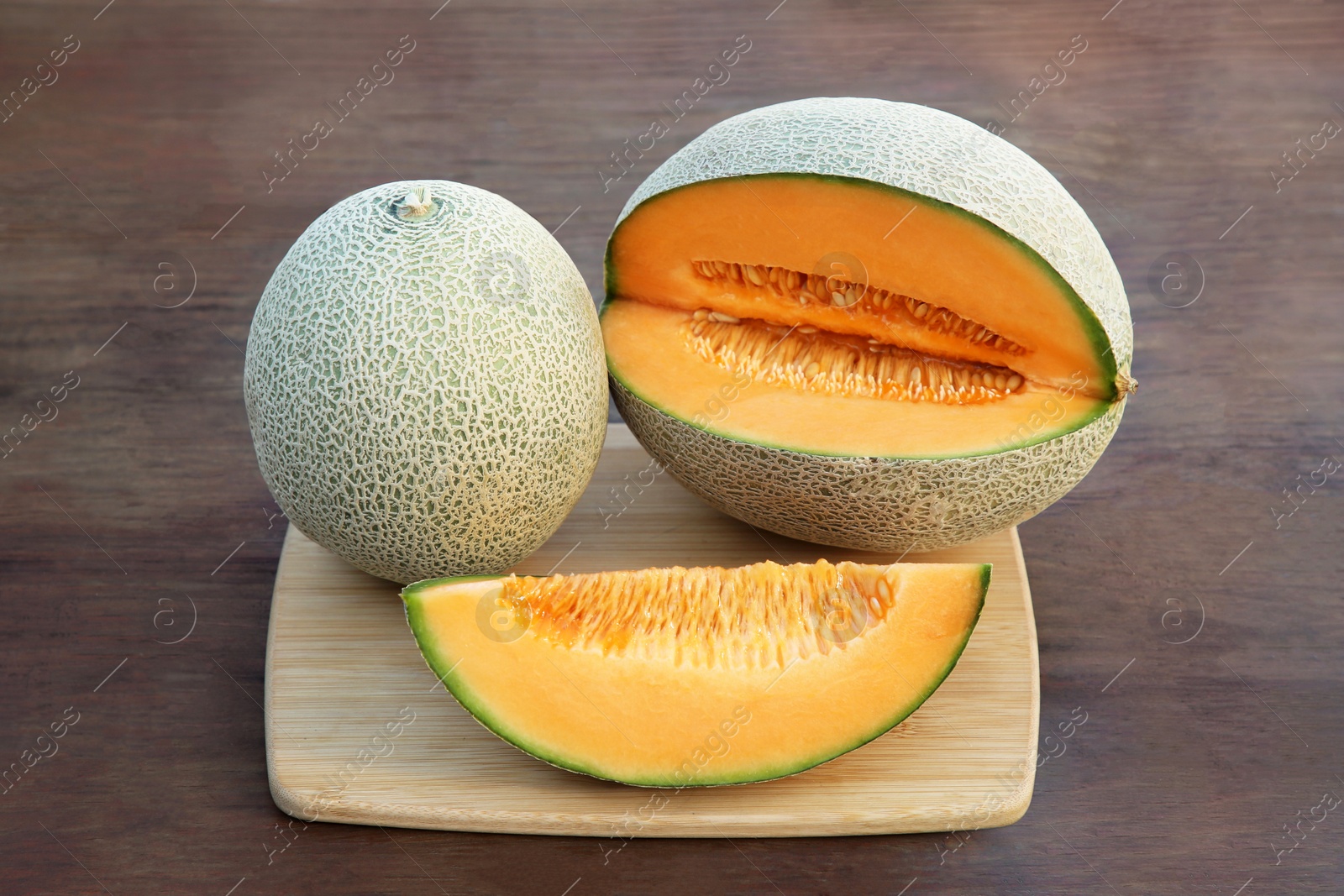 Photo of Whole and cut delicious ripe melons on wooden table