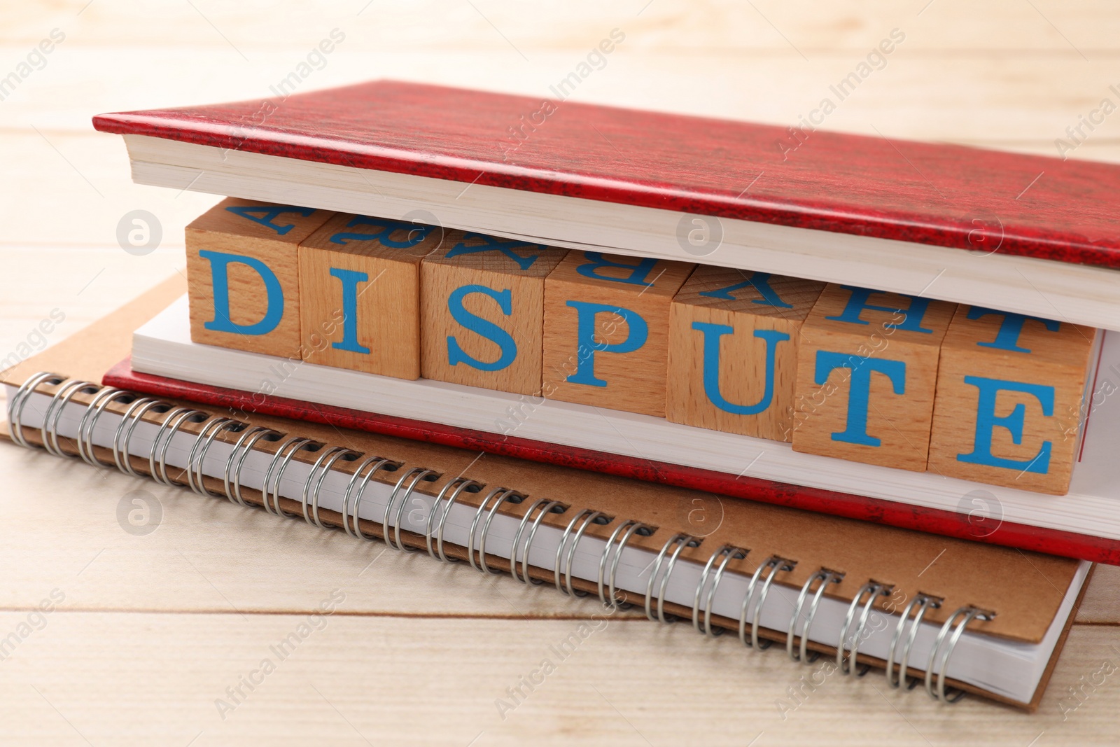 Photo of Cubes with word Dispute and notebooks on wooden table, closeup