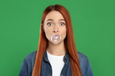 Photo of Surprised woman blowing bubble gum on green background