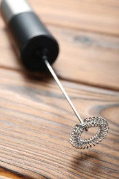 Black milk frother wand on wooden table, closeup