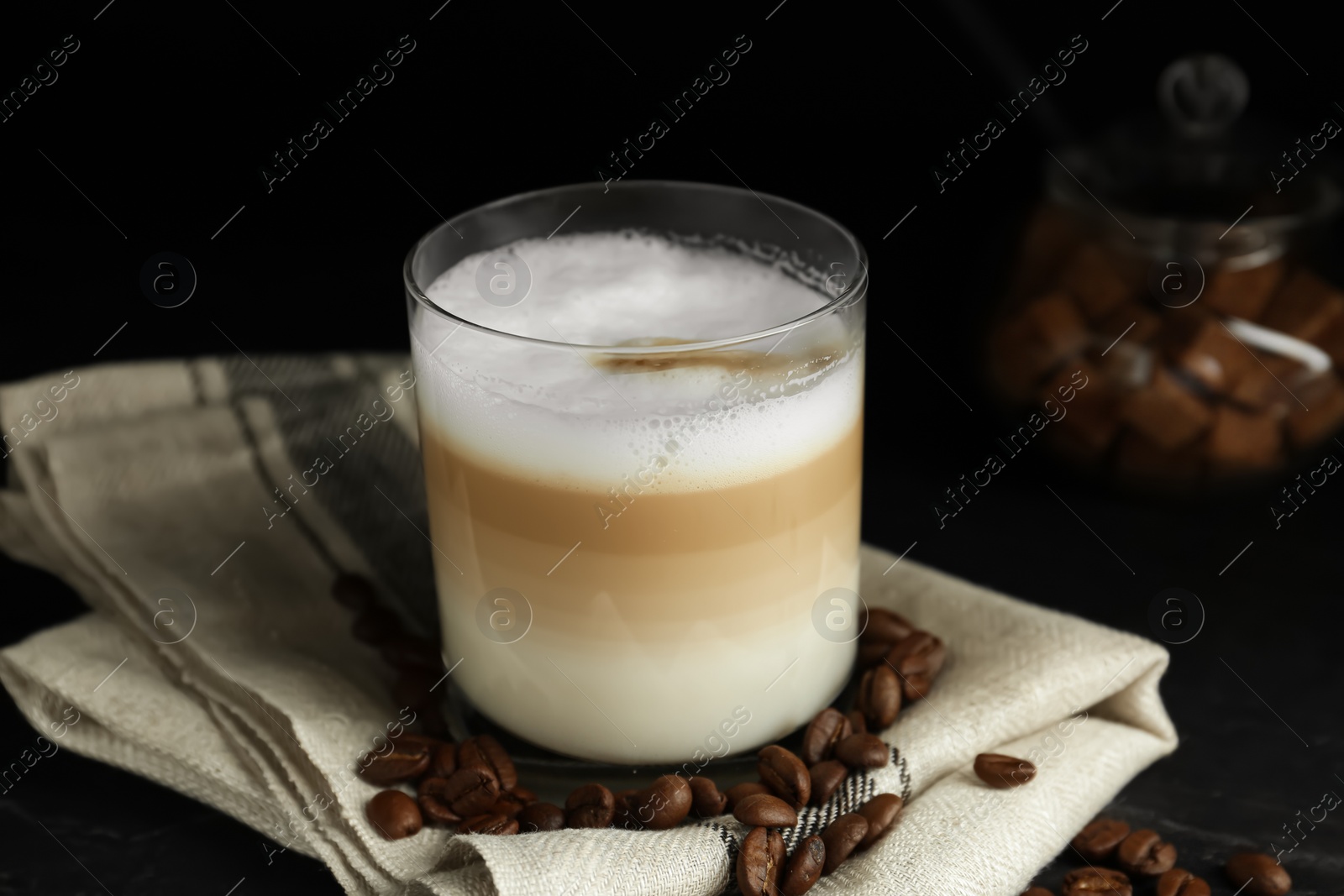 Photo of Delicious latte macchiato and coffee beans on black table