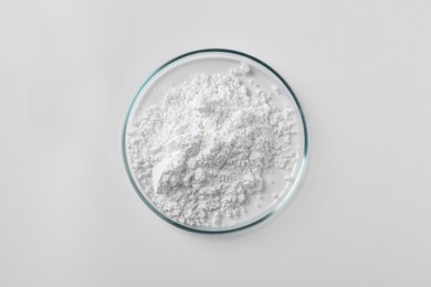 Photo of Petri dish with calcium carbonate powder on white background, top view