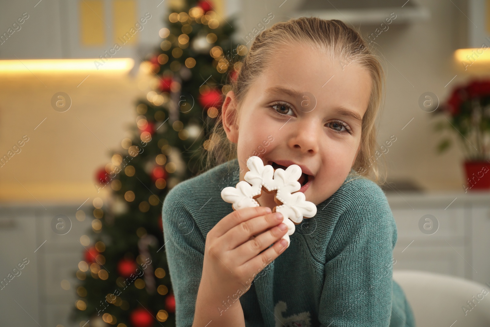 Photo of Cute little girl with Christmas gingerbread cookie at home