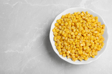 Photo of Delicious canned corn in bowl on marble table, top view. Space for text