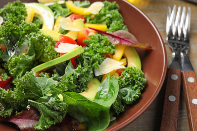 Photo of Tasty fresh kale salad on wooden table, closeup