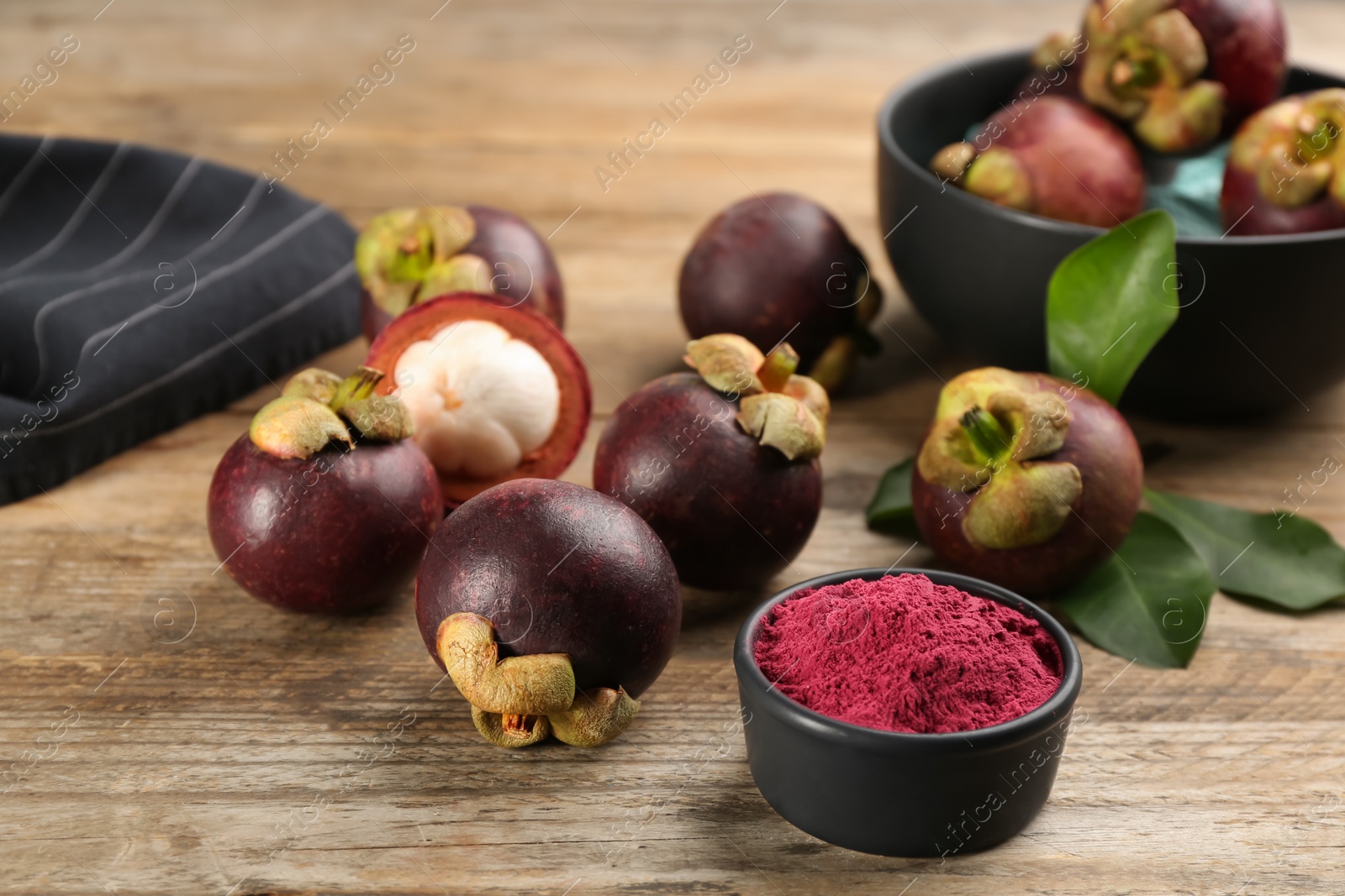 Photo of Purple mangosteen powder and fruits on wooden table
