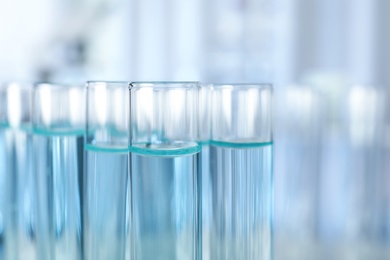 Test tubes with liquid on blurred background, closeup. Laboratory analysis