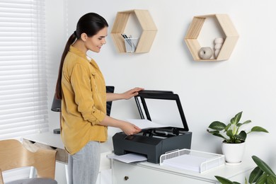 Woman using modern printer at workplace indoors