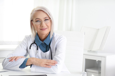 Portrait of mature female doctor in white coat at workplace