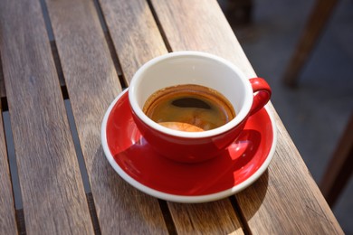 Photo of Cup of aromatic hot coffee on wooden table outdoors