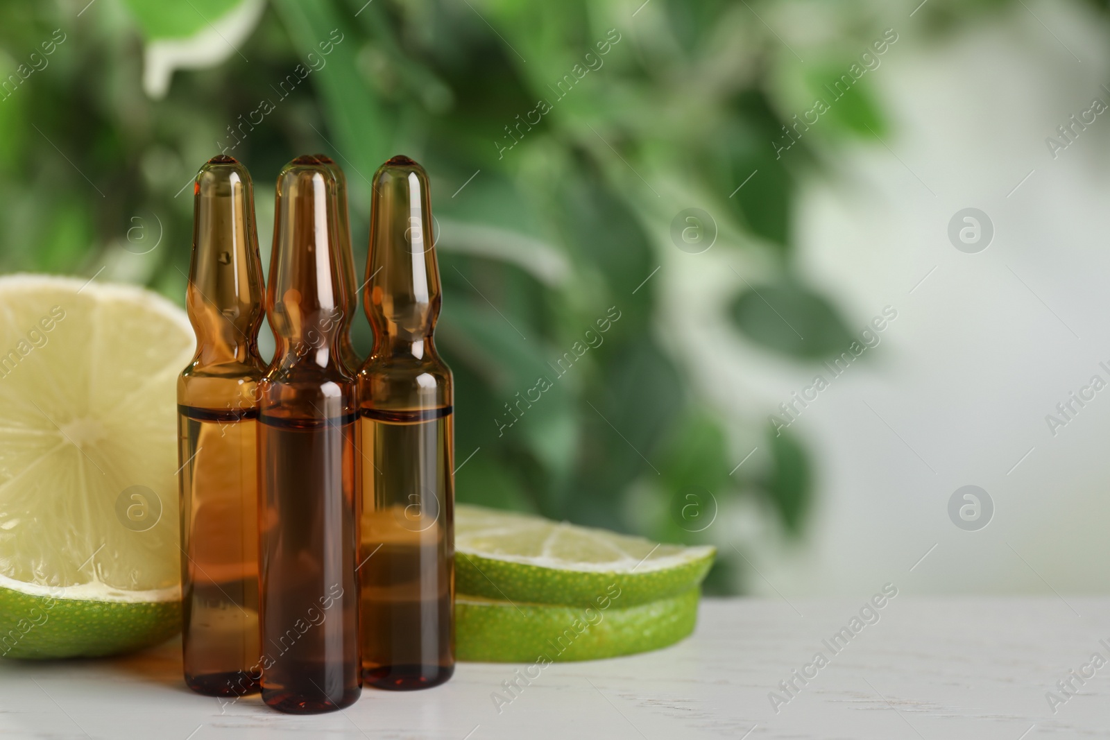 Photo of Pharmaceutical ampoules with medication and fresh lime on white table, closeup. Space for text