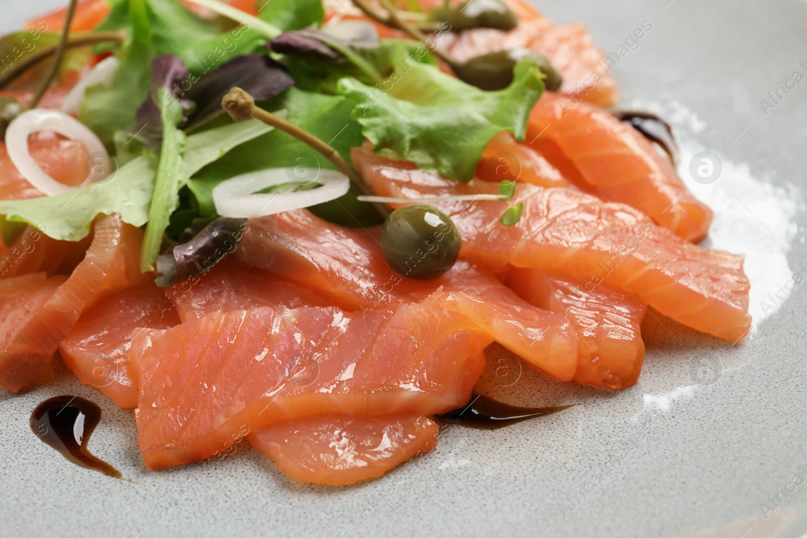 Photo of Delicious salmon carpaccio with capers on plate, closeup