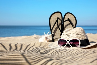 Photo of Stylish beach accessories on sand near sea