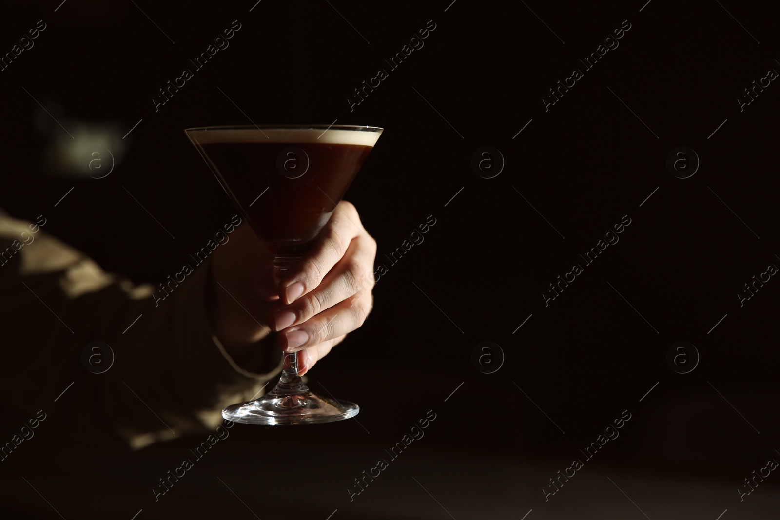 Photo of Barman holding espresso martini cocktail in darkness, closeup. Space for text