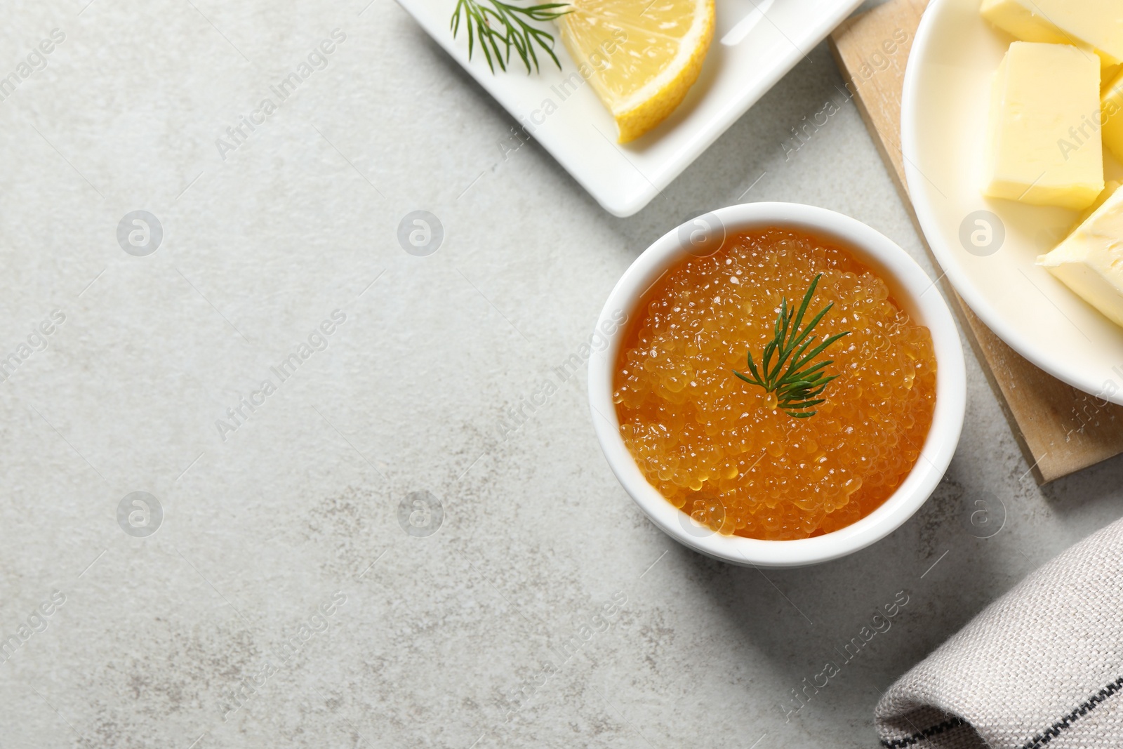 Photo of Fresh pike caviar, dill, butter and lemon on light grey table, top view. Space for text