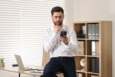 Photo of Portrait of handsome man with smartphone in office